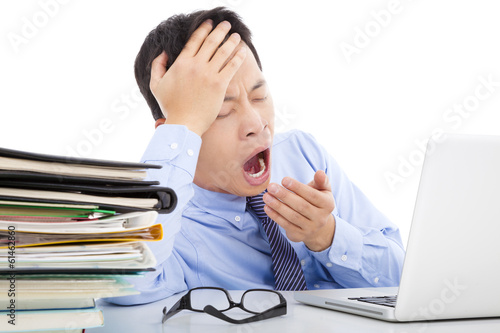 Photo: Exhausted young businessman yawning and holding his head Exhausted young businessman yawning and holding his head