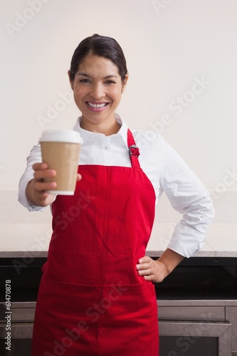 Photo: Pretty young barista offering cup of coffee to go Pretty young barista offering cup of coffee to go
