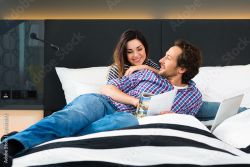 Photo: Young couple in Hotel in bed with wifi and computer Young couple in Hotel in bed with wifi and computer