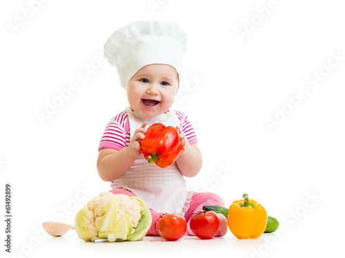 Photo: cute baby chef with healthy food vegetables, isolated on white cute baby chef with healthy food vegetables, isolated on white