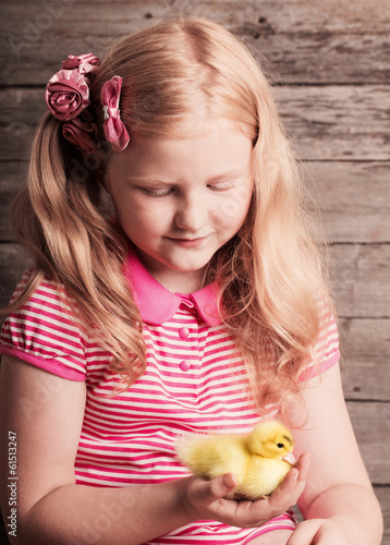 Photo: girl with gosling on wooden background girl with gosling on wooden background