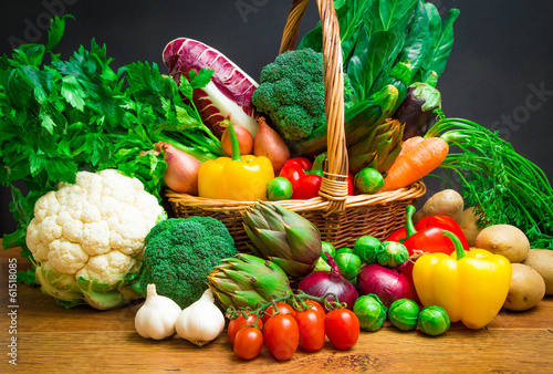Photo: Raw vegetables in wicker basket on wooden table Raw vegetables in wicker basket on wooden table