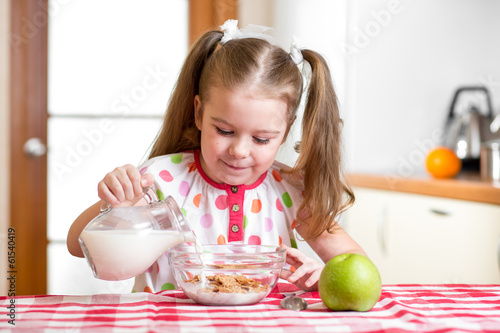 Photo: kid girl preparing corn flakes with milk kid girl preparing corn flakes with milk
