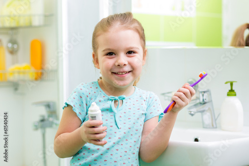 Photo: Child girl brushing teeth in bathroom Child girl brushing teeth in bathroom