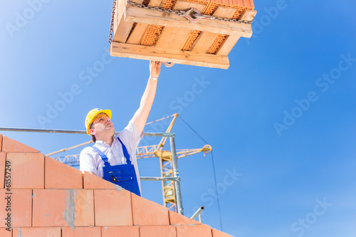 Photo: Maurer bekommt eine Palette Backsteine auf Baustelle Maurer bekommt eine Palette Backsteine auf Baustelle