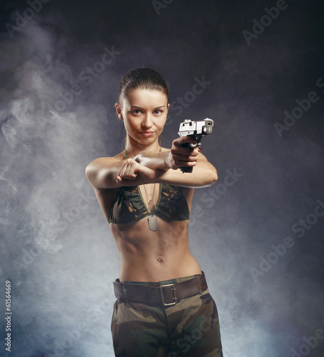 Photo: Beautiful redhead young woman with gun and military outfit, on s Beautiful redhead young woman with gun and military outfit, on s