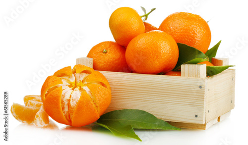 Photo: Ripe tasty tangerines with leaves in wooden box isolated Ripe tasty tangerines with leaves in wooden box isolated