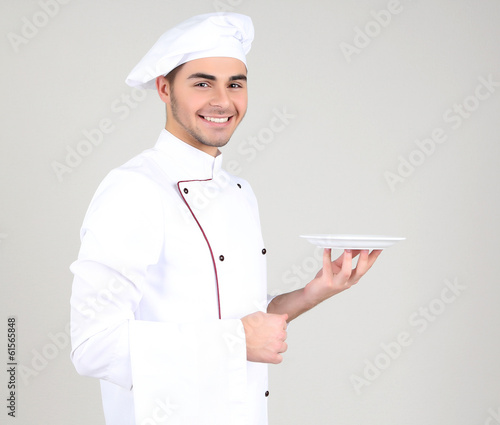 Photo: Professional chef in white uniform and hat, on gray background Professional chef in white uniform and hat, on gray background