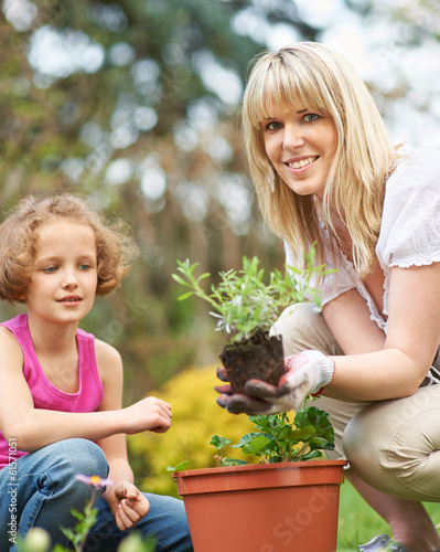 Photo: Mädchen und Mutter pflanzen Blumen im Garten Mädchen und Mutter pflanzen Blumen im Garten