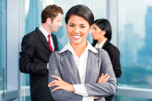 Photo: Asian business team in office, woman in front with skyline Asian business team in office, woman in front with skyline