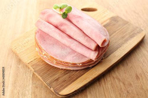 Photo: Tasty ham with sunflower sprouts on wooden background Tasty ham with sunflower sprouts on wooden background