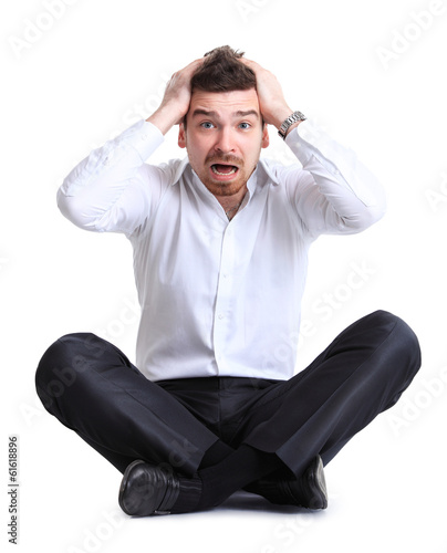Photo: business man sitting on the floor with shocked facial expression business man sitting on the floor with shocked facial expression
