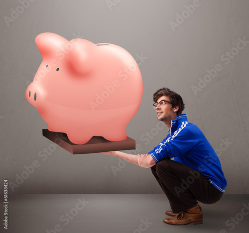 Photo: Handsome man holding a huge savings piggy bank Handsome man holding a huge savings piggy bank