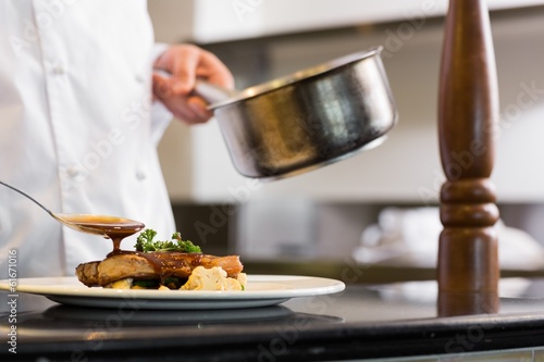 Photo: Closeup mid section of a chef garnishing food Closeup mid section of a chef garnishing food