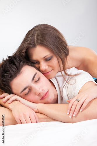 Photo: Portrait of happy young couple lying in bed and smiling Portrait of happy young couple lying in bed and smiling