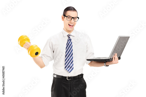 Photo: Young businessman holding dumbbell and laptop Young businessman holding dumbbell and laptop