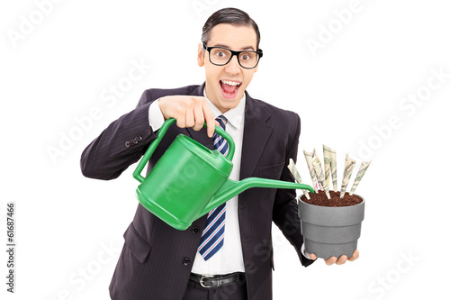 Photo: Young businessman watering money in a flowerpot Young businessman watering money in a flowerpot