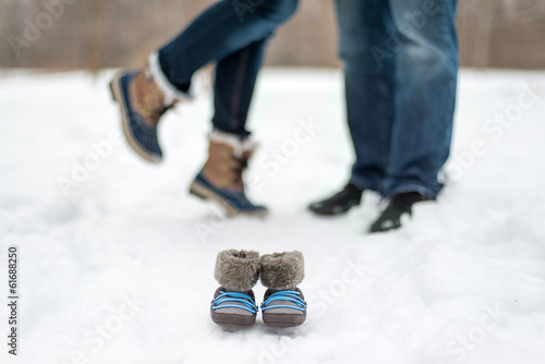 Photo: detail of baby boots and expecting couple enjoying a snowy day detail of baby boots and expecting couple enjoying a snowy day