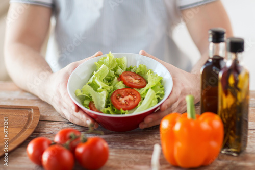 Photo: close of male hand holding a bowl with salad close of male hand holding a bowl with salad