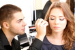 Young guy stylist doing makeup beautiful woman in beauty salon Young guy stylist doing makeup beautiful woman in beauty salon