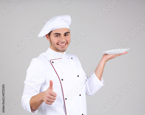 Photo: Professional chef in white uniform and hat, on gray background Professional chef in white uniform and hat, on gray background