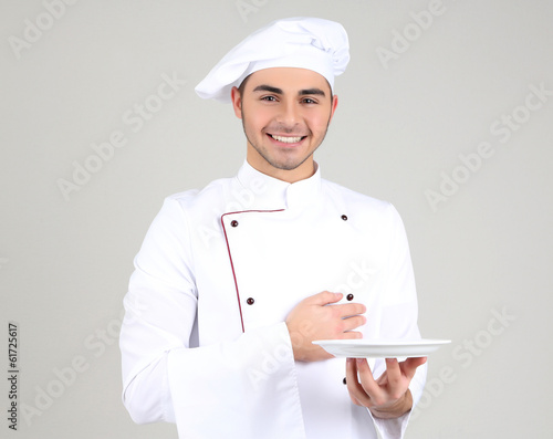 Photo: Professional chef in white uniform and hat, on gray background Professional chef in white uniform and hat, on gray background