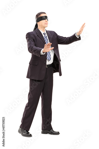 Photo: Full length portrait of a blindfolded businessman in suit Full length portrait of a blindfolded businessman in suit