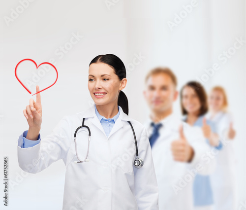Photo: smiling female doctor pointing to heart smiling female doctor pointing to heart