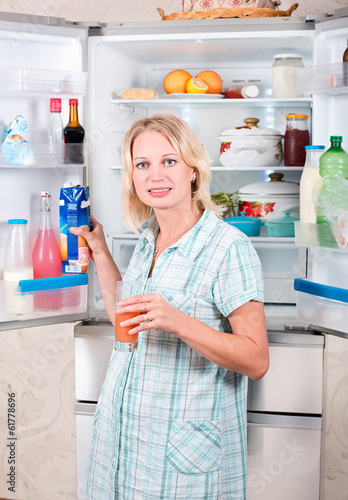 Photo: Young beautiful girl takes food from the refrigerator. Young beautiful girl takes food from the refrigerator.