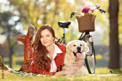 Photo: Pretty female lying down with dog in park Pretty female lying down with dog in park