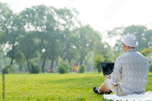 Photo: young man working in the park with a laptop young man working in the park with a laptop