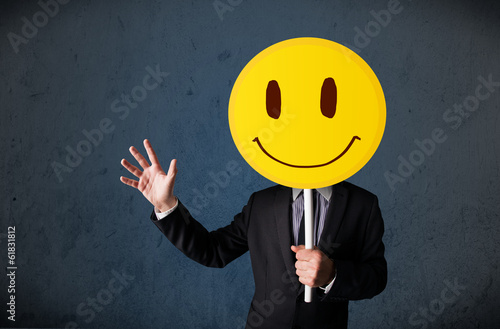 Photo: Businessman holding a smiley face emoticon Businessman holding a smiley face emoticon