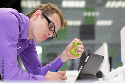Photo: business man office squeezing stress sponge looking at tabley business man office squeezing stress sponge looking at tabley