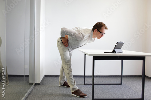Photo: exercise durrng office work - man with tablet in his office exercise durrng office work - man with tablet in his office