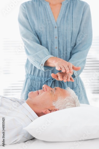 Photo: Therapist performing Reiki over forehead of man Therapist performing Reiki over forehead of man