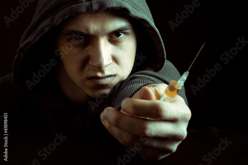 Photo: Grunge image of a depressed drug addict looking at a syringe Grunge image of a depressed drug addict looking at a syringe
