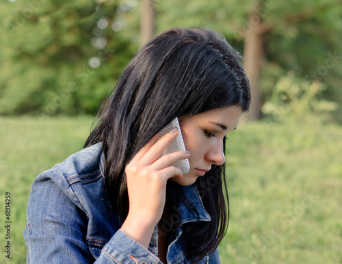 Photo: Young girl listening to a call on her mobile Young girl listening to a call on her mobile