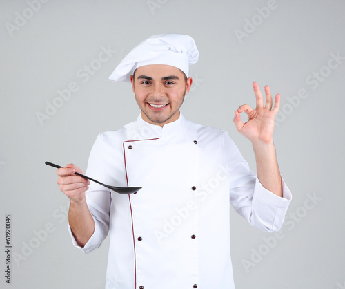 Photo: Professional chef in white uniform and hat, on gray background Professional chef in white uniform and hat, on gray background