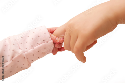 Photo: Newborn baby holding finger of older kid. Newborn baby holding finger of older kid.