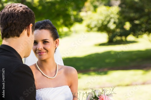 Photo: Romantic newlywed couple looking at each other in park Romantic newlywed couple looking at each other in park