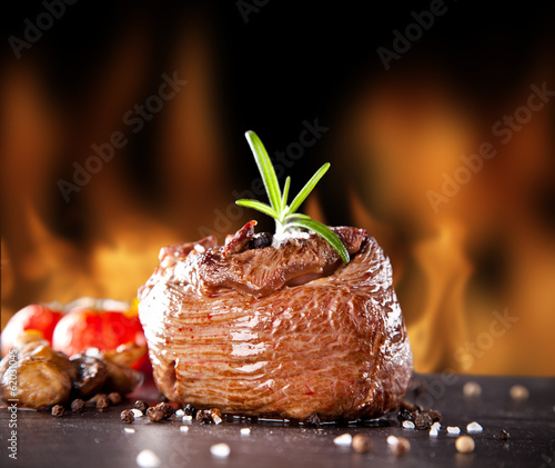 Photo: Fresh beef steak on black stone and fire Fresh beef steak on black stone and fire
