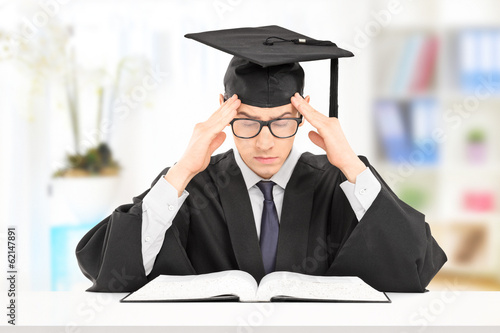 Photo: Male student in graduation gown studying indoors Male student in graduation gown studying indoors