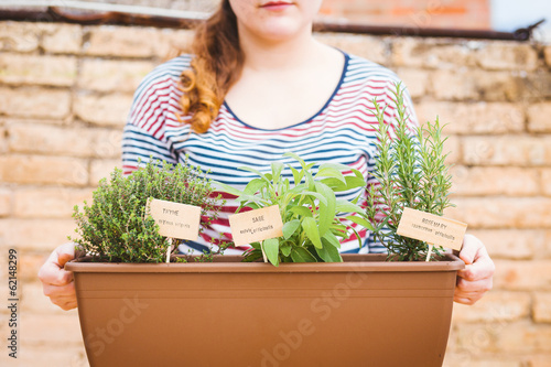Photo: Young woman holding pot of aromatic herbs Young woman holding pot of aromatic herbs