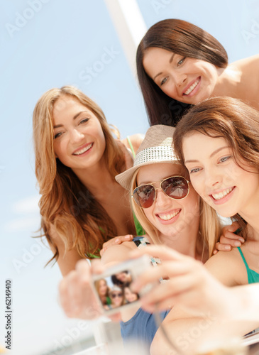 Photo: smiling girls taking photo in cafe on the beach smiling girls taking photo in cafe on the beach