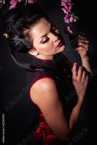 Photo: Beautiful woman studio portrait with flower branch Beautiful woman studio portrait with flower branch