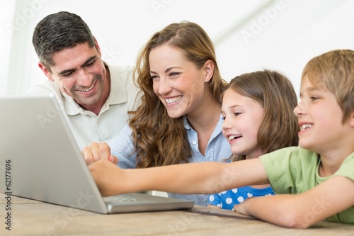 Photo: Smiling family using laptop Smiling family using laptop