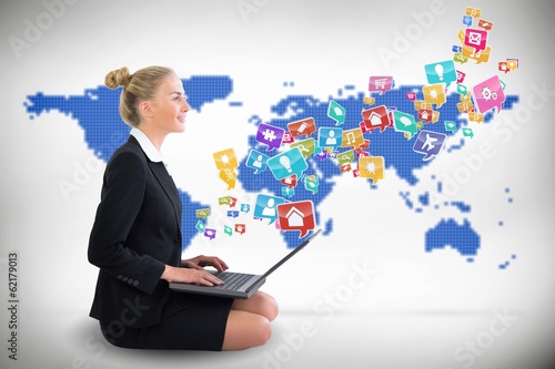 Photo: Blonde businesswoman sitting using laptop with app icons Blonde businesswoman sitting using laptop with app icons