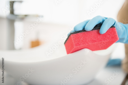 Photo: Closeup on housewife cleaning sink with sponge Closeup on housewife cleaning sink with sponge