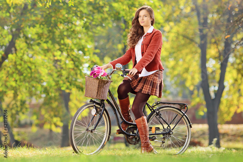 Photo: Beautiful female on her bicycle in a park Beautiful female on her bicycle in a park