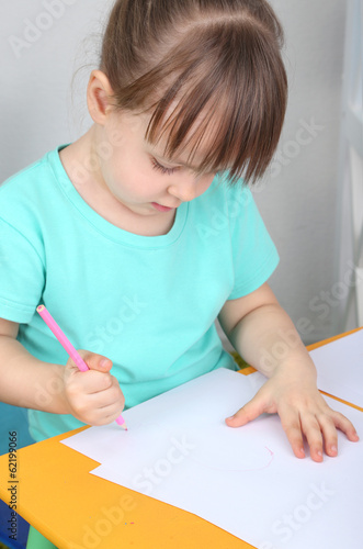 Photo: Little girl draws sitting at table in room Little girl draws sitting at table in room